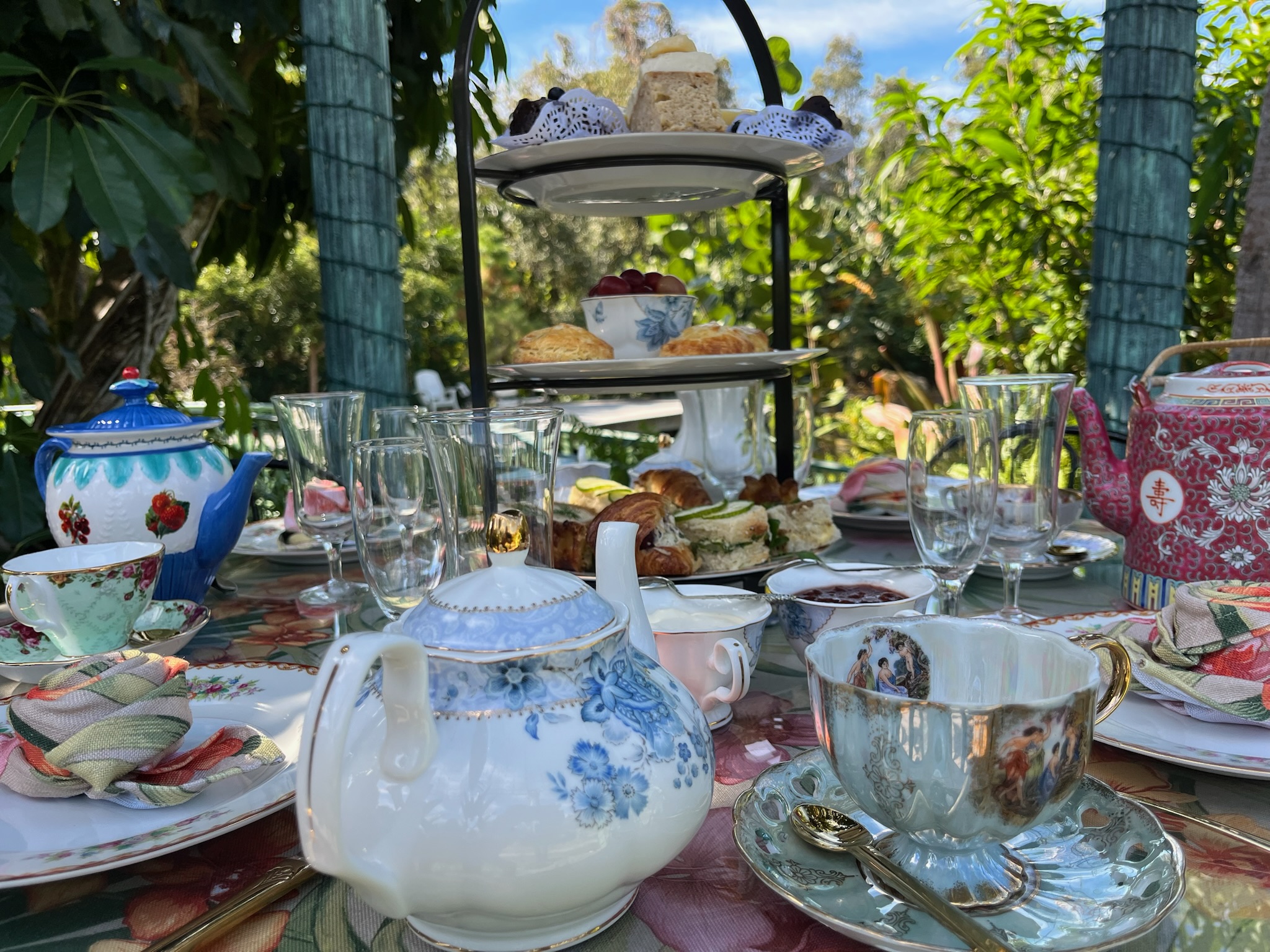 Close-up of fine teapots, teacups, and tiered stand with treats